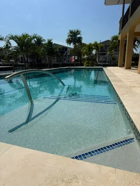Pool with entry steps and handrail along waterfront canal
