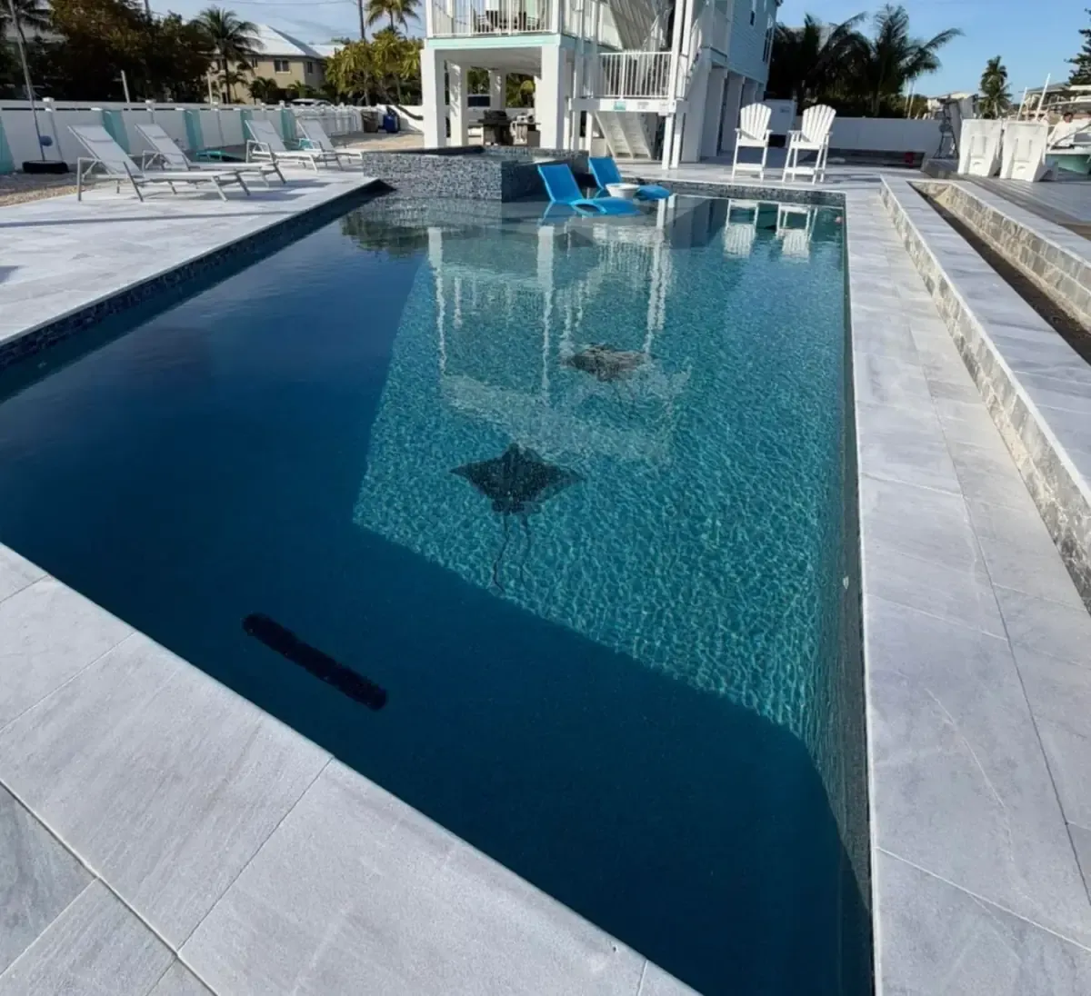 Rectangular pool running parallel to the canal with colorful Adirondack chairs and waterfront views