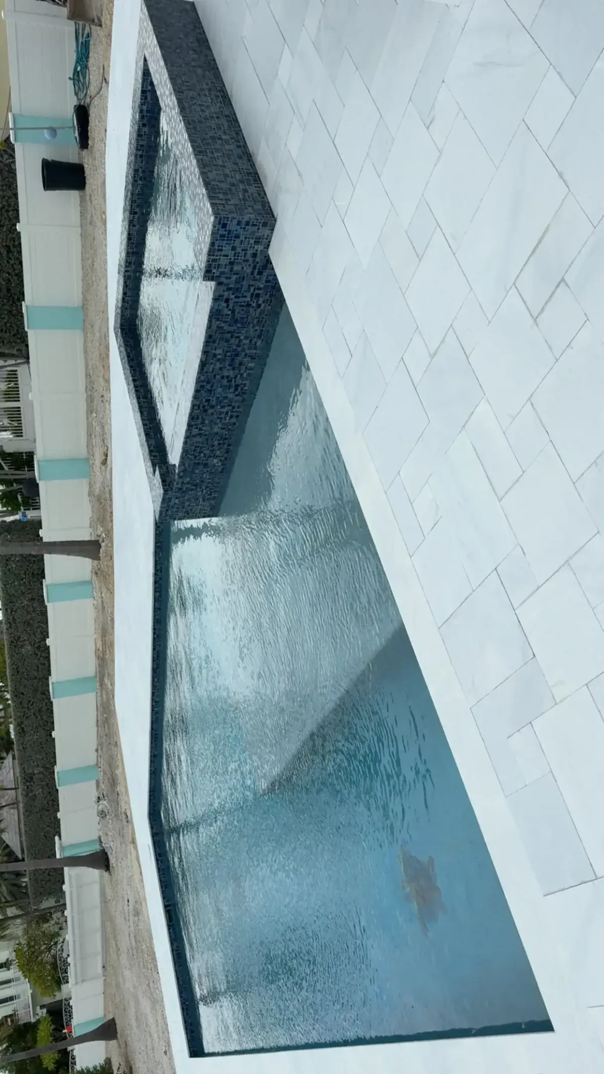 Waterfront pool with in-water loungers, built-in grill, shaded patio, and open canal views