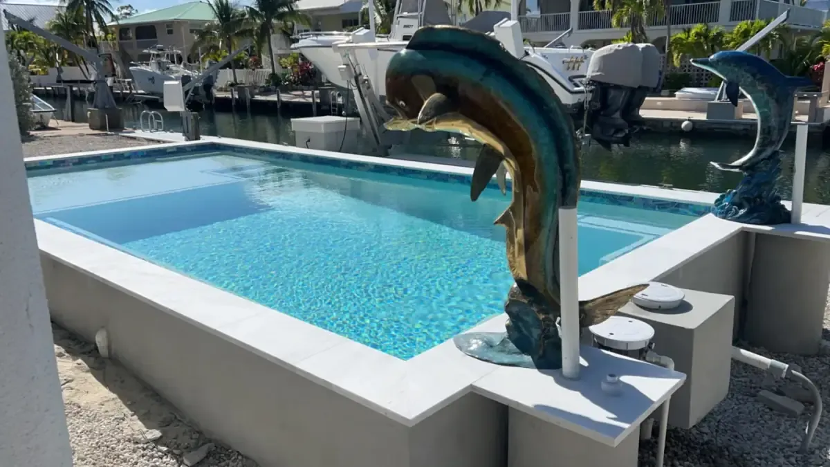 Freeform waterfront pool with sun shelf, diving board, tanning ledge, and canal views