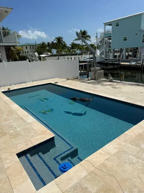 Wide overhead view of pool with mosaics, dock, and marina background