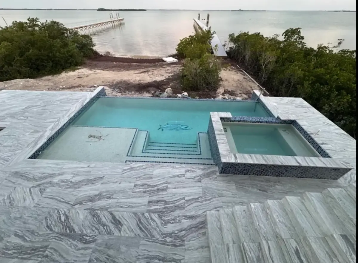 Overhead view of pool and spa with fish mosaic on marble deck